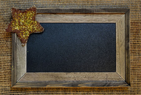 Framed script ready chalkboard. Twinkling gold star in corner. Frame set on rustic mesh.の写真素材