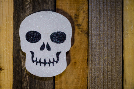 Halloween decor.  Spooky sparkle white skull set on pallet wood.  Celebration and scary fun for Autumn Holiday.の写真素材