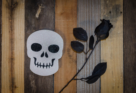 Black and white glitter skull and black rose set on pallet wood.  Celebrate Halloween with seasonal decor.の写真素材