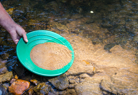 Panning for gold in mineral rich stream. Fun and adventure in this outdoor recreational activity of prospecting for gold and gem stones.の写真素材