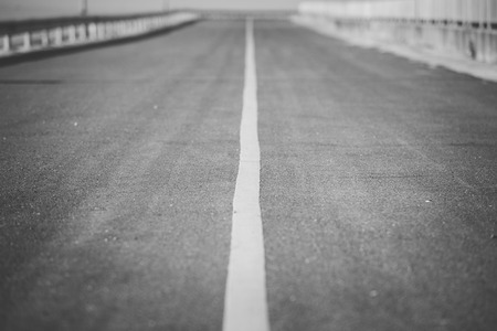 White direct line on asphalt road over black and white backgroundの写真素材