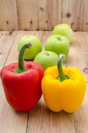 Colorful bell pepper and green apples on wooden panelの写真素材