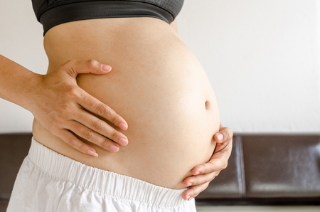 Close up pregnant women touching her belly with handsの写真素材