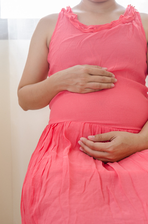 Close up pregnant women touching her belly with handsの写真素材