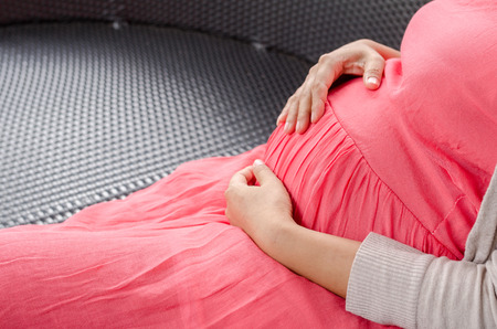 Close up pregnant women touching her belly with handsの写真素材