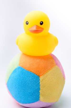 Yellow duck toy on toy soccer ball with white backgroundの写真素材