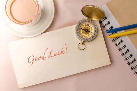 Good luck message and vintage compass on wooden bord with coffee cup.の写真素材