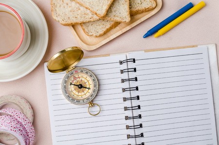 Office table with blank notepad, vintage compass and coffee cup on fabric background. Top view with copy spaceの写真素材
