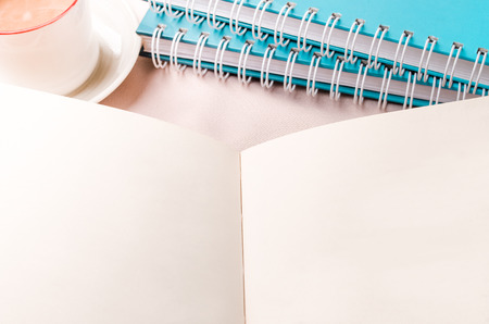 Office table with blank notepad and coffee cup on fabric background. Top view with copy space