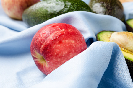 Close-up of red apple with avocado on blue backgroundの写真素材