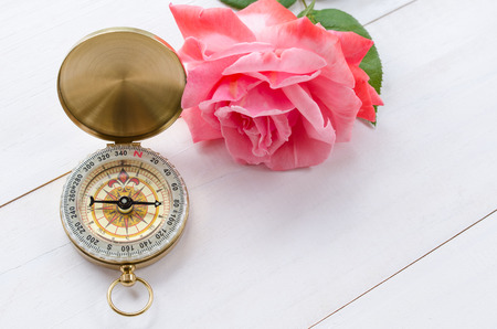 Compass with beautiful pink rose on a white wooden backgroundの写真素材
