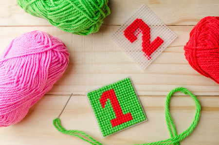 Plastic Canvas, hand made with red yarn number on wooden background.
