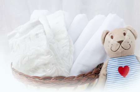 Set of diapers for newborn in basket with love bear toy. Baby clothes preparation.の写真素材
