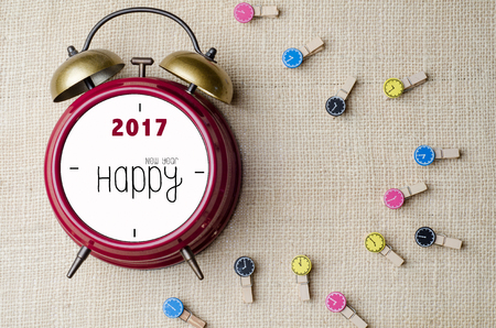 Red retro alarm bell clock with Happy New Year 2017 and clothes pin on burlap sack backgroundの写真素材