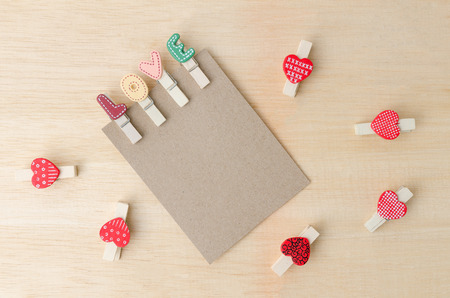 Blank paper note with love clips and red hearts on wooden backgroundの写真素材