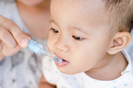 Mother teaching baby girl teeth brushingの写真素材