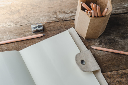 Blank daily planner notebook with pencils and pencil sharpener on wooden backgroundの写真素材