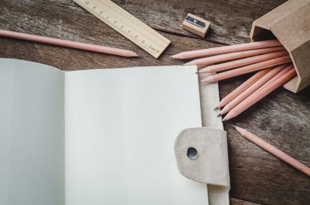 Blank daily planner notebook with pencils,  pencil sharpener and ruler on wooden backgroundの写真素材