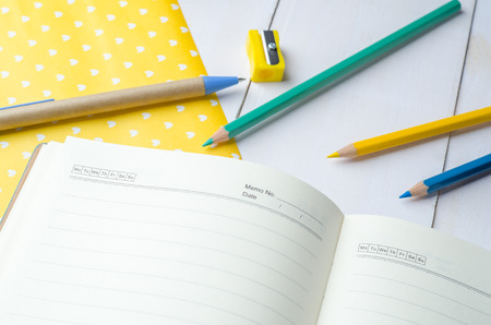 Blank daily planner notebook with pen and color pencils on white wooden backgroundの写真素材