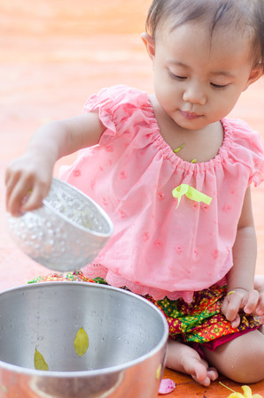Asian toddler girl with traditional thai costumes enjoy splashing water during Thailand Water Festival (Songkran Day)の写真素材