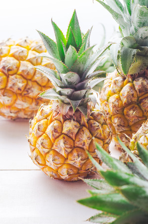 Ripe pineapples on white wooden table backgroundの写真素材