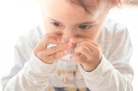 Asian little girl takes medicine syrup by herselfの写真素材