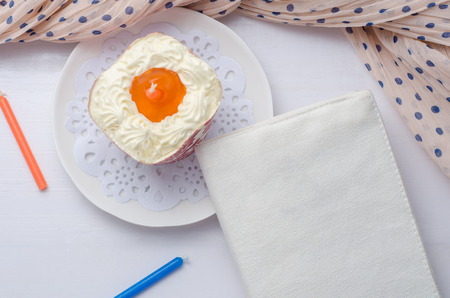 Blank notebook with candle and cupcake on wooden table.の写真素材