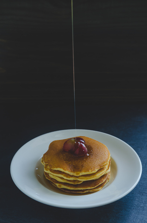 Pancakes with fresh fruit and honey on black stone backgroundの写真素材