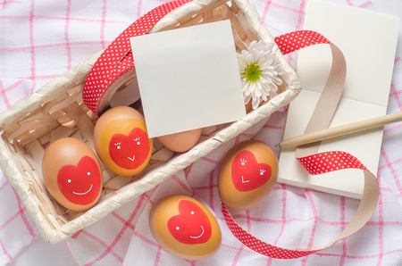 White paper note and egg with red heart on basketの写真素材