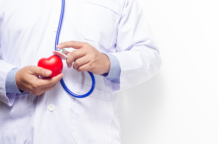 Doctor holding red heart with stethoscope on white wooden background.の写真素材