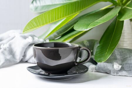 Coffee mug black with leaves on white wooden tableの写真素材
