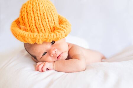 Little cute baby boy lying on the bed with a knitted hatの写真素材