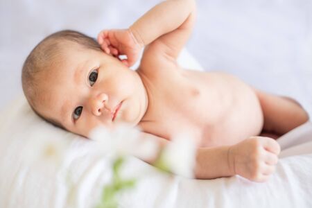 Newborn baby boy lying on white bed at homeの写真素材
