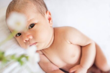 Newborn baby boy lying on white bed at homeの写真素材