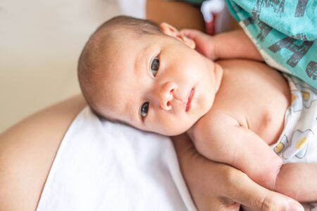 Newborn baby boy relaxing lay down on the lap of his mother