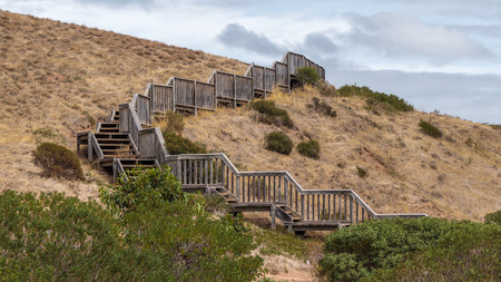 a wooden boardwalk up to the hill surrounded with dry grass