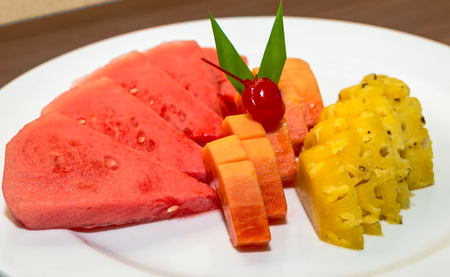 slices of pineapple, watermelon, papaya, and cherry on top served on white plateの写真素材