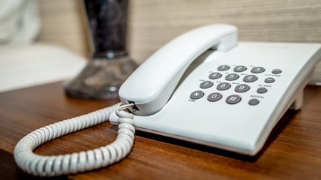 white desk cord telephone with grey numbers on the tableの写真素材