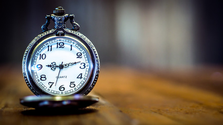 Old and antique pocket watch on wooden floor with blurred backgroundの写真素材