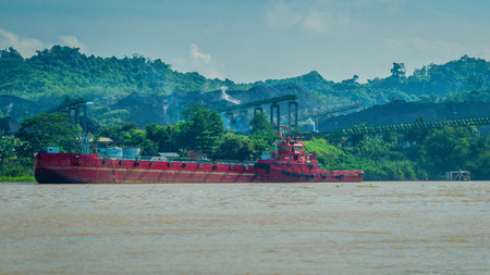 A tugboat approaching coal stockpile on Mahakam riverbank, Borneo, Indonesiaの写真素材