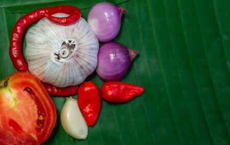 Asian ingredients lay on banana leaf. slice of tomato, onion, garlic, and chiliの写真素材