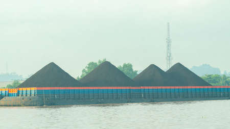 Barge full of black coal crossing Mahakam riverの写真素材
