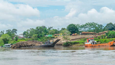 Timber loaded into big barge then drag by a tugboat cruising Mahakam River, Borneo, Indonesiaの写真素材