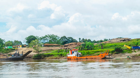 Timber loaded into big barge then drag by a tugboat cruising Mahakam River, Borneo, Indonesiaの写真素材