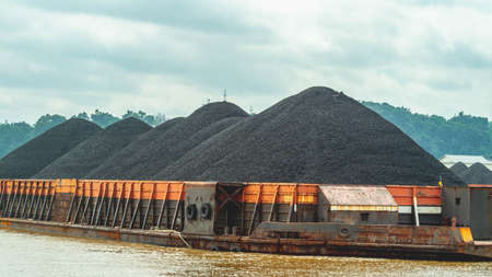 Barge full of black coal cruising on Mahakam River, Borneo, Indonesia. Mining and energyの写真素材