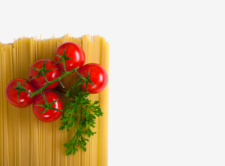 Uncooked pasta with fresh tomatoes and parsley on a white backgroundの写真素材