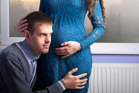 The husband is listenning to his pregnant wife's tummy