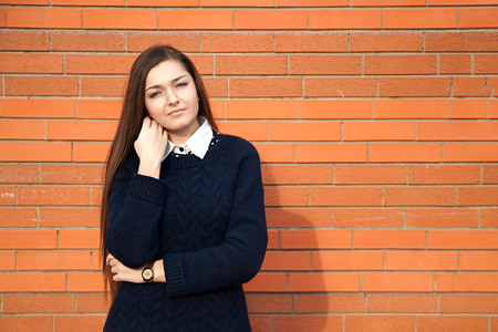 Young woman straightens her hair on a red wallの写真素材