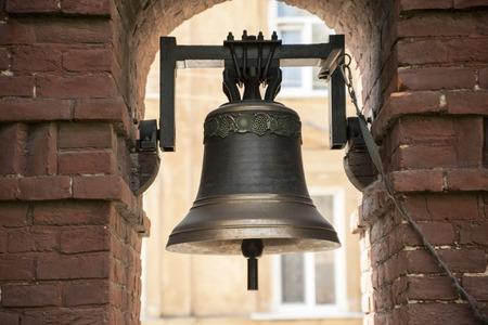 The old bronze bell near the brick wallの写真素材