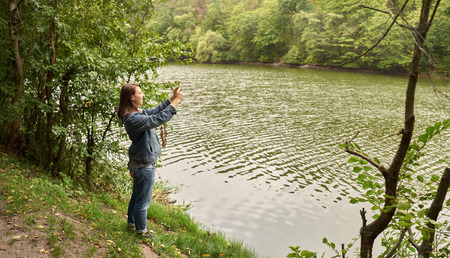 woman taking pictures on the river bankの写真素材